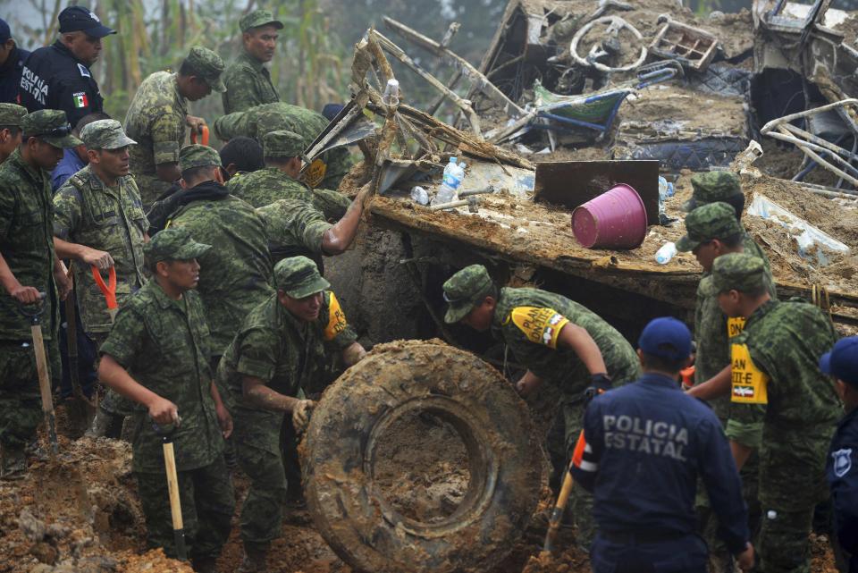 Soldiers and police work around the wreckage of a bus after it was buried by a mountain landslide at Altotonga in Veracruz state