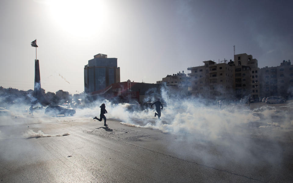 Palestinian demonstrators run from tear gas fired by Israeli troops during the protest against the U.S. announcement that it no longer believes Israeli settlements violate international law., at checkpoint Beit El near the West Bank city of Ramallah, Tuesday, Nov. 26, 2019, (AP Photo/Majdi Mohammed)