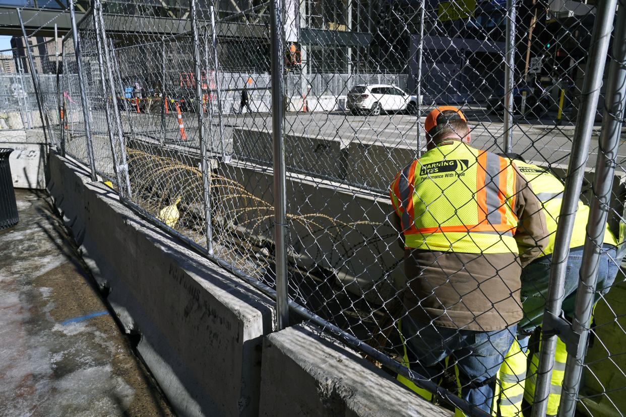 Varios trabajadores instalan alambre de navajas entre barreras en los alrededores del Centro de Gobierno del condado de Hennepin, el miércoles 23 de febrero de 2021, en Minneapolis, como parte de las medidas de seguridad en preparación para el juicio del expolicía de Minneapolis Derek Chauvin, acusado de matar a George Floyd durante un arresto en mayo pasado en Minneapolis. (AP Foto/Jim Mone)