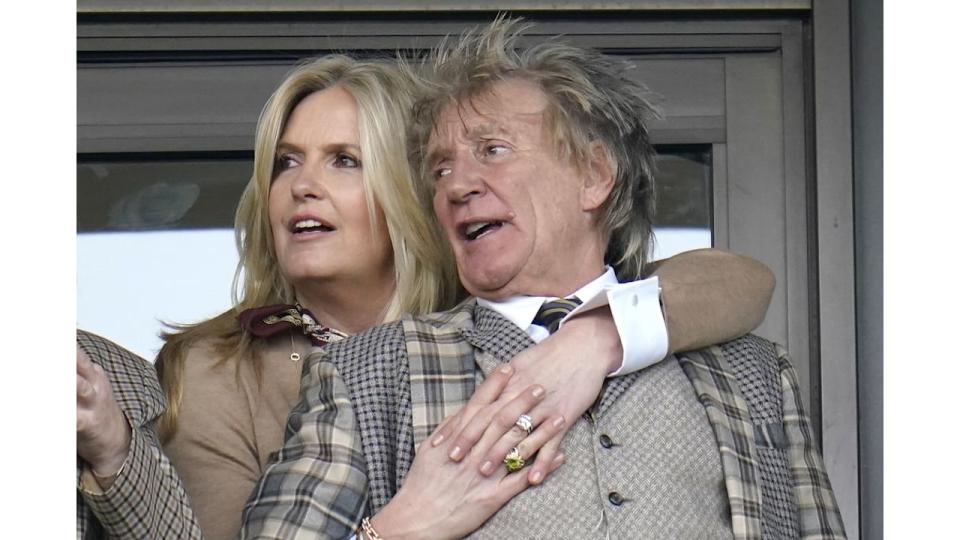 Penny Lancaster hugging Rod Stewart from behind