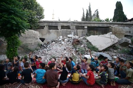 Children look at a drone that belongs to Adaleh Foundation as they are gathered amidst damaged buildings during Iftar (breaking fast), during the holy month of Ramadan in the rebel-held besieged town of Douma to the east of Damascus, Syria, June 20, 2017. REUTERS/Bassam Khabieh SEARCH "IFTAR ADALEH" FOR THIS STORY. SEARCH "WIDER IMAGE" FOR ALL STORIES.