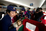 Stewardesses offer tea to journalists aboard a high-speed train in Hebei province south of Beijing on December 22, 2012. China showed off the final link of the world's longest high-speed rail route, set to open on December 26, stretching from Beijing to the southern Chinese city of Guangzhou. Travelling at around 300 kph, trains on the new route are expected to cover the 2,298-kilometre (1,425-mile) journey in a third of the current time from 22 hours to eight. AFP PHOTO / Ed Jones