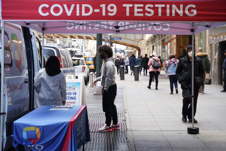 A few people wait outside a mobile van dispensing COVID-19 tests on a street in Manhattan.