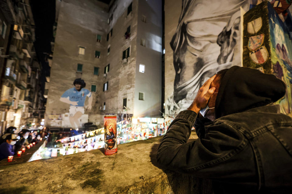 People gather and light candles under a mural of soccer legend Diego Maradona, in Naples, Italy, Wednesday, Nov. 25, 2020. Diego Maradona has died. The Argentine soccer great was among the best players ever and who led his country to the 1986 World Cup title before later struggling with cocaine use and obesity. He was 60. (Alessandro Garofalo/LaPresse via AP)