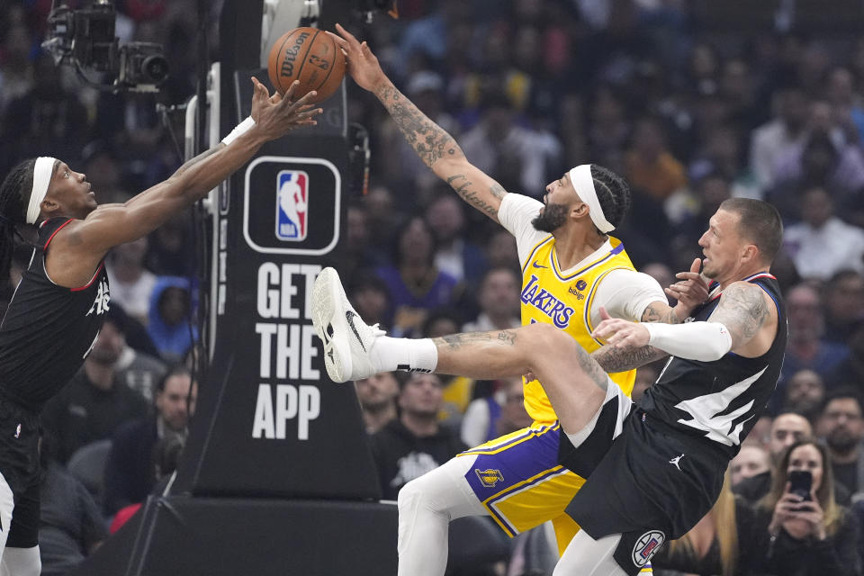 Los Angeles Lakers forward Anthony Davis, center, reaches for a rebound with Los Angeles Clippers guard Terance Mann, left, and center Daniel Theis during the first half of an NBA basketball game Wednesday, Feb. 28, 2024, in Los Angeles. (AP Photo/Mark J. Terrill)