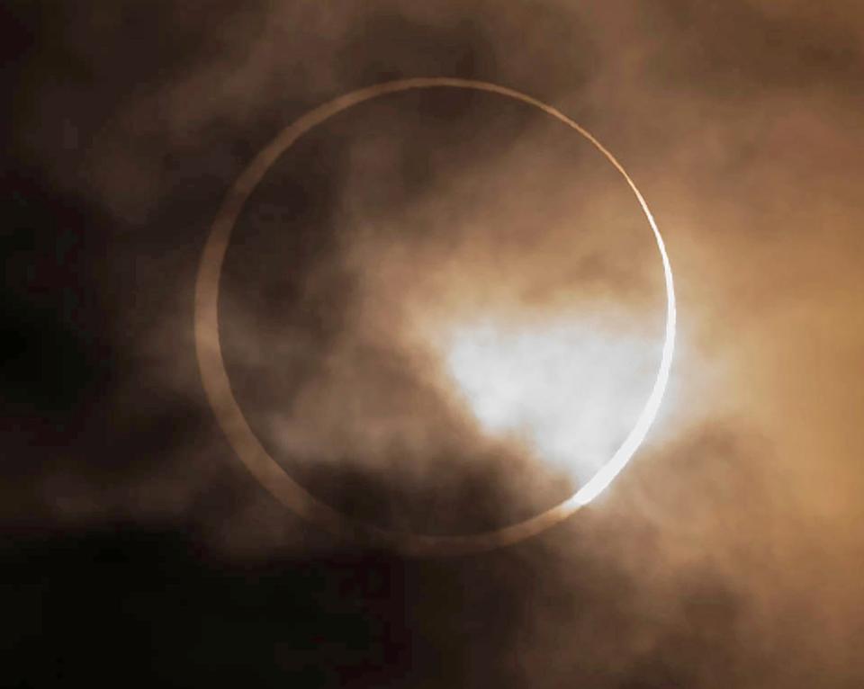 An annular solar eclipse appears from behind clouds in Eugene, Oregon, on Saturday, Oct. 14, 2023.