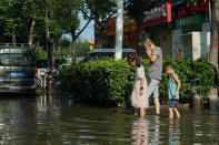 People walk along a flooded street in Xinxiang in central China's Henan Province, Monday, July 26, 2021. Forecasters Monday said more heavy rain is expected in central China's flood-ravaged Henan province, where the death toll continues to rise after flash floods last week that killed dozens of people. (AP Photo/Dake Kang)