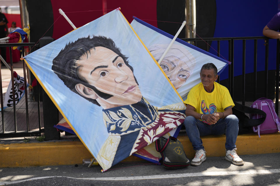 Un simpatizante del presidente Nicolás Maduro sentado junto a un cartel con la imagen del héroe de la independencia venezolana Simón Bolívar mientras espera para el inicio del acto de cierre de campaña de Maduro en Caracas, Venezuela, el jueves 25 de julio de 2024. Venezuela va a elecciones presidenciales el domingo 28 de julio. (AP Foto/Fernando Vergara)