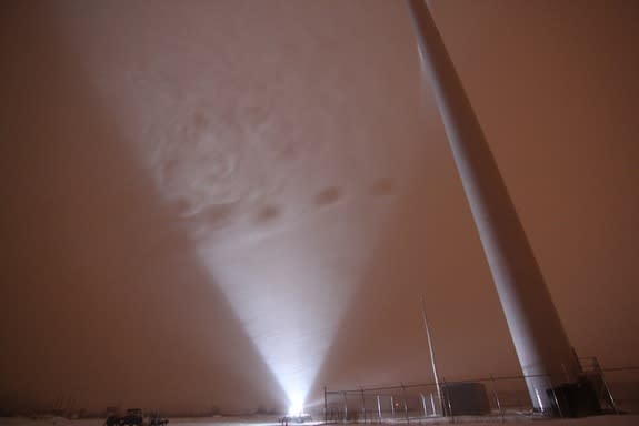 Snowflakes falling behind a wind turbine are illuminated parallel to the wind direction.