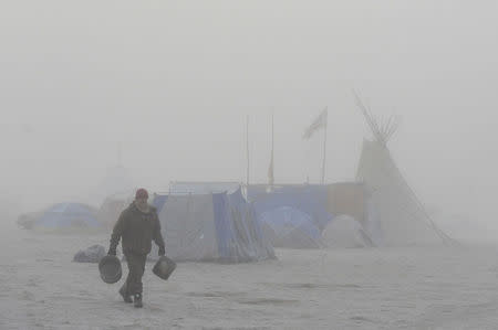 A man walks with water buckets in the mist in the Oceti Sakowin camp during a protest against the Dakota Access pipeline near the Standing Rock Indian Reservation near Cannon Ball, North Dakota, U.S. November 11, 2016. REUTERS/Stephanie Keith