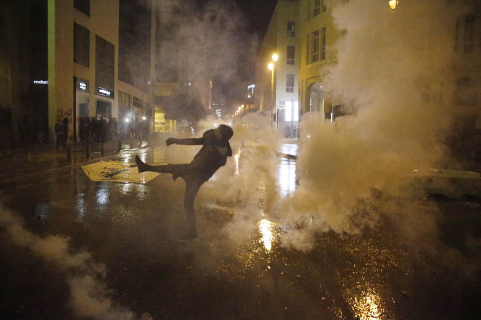 An anti-government demonstrator throws back tear gas at riot police during ongoing protests in Beirut, Lebanon, Wednesday, Jan. 22, 2020. Lebanon's new government held its first meeting Wednesday, a day after it was formed following a three-month political vacuum, with the prime minister saying his Cabinet will adopt financial and economic methods different than those of previous governments. (AP Photo/Bilal Hussein)