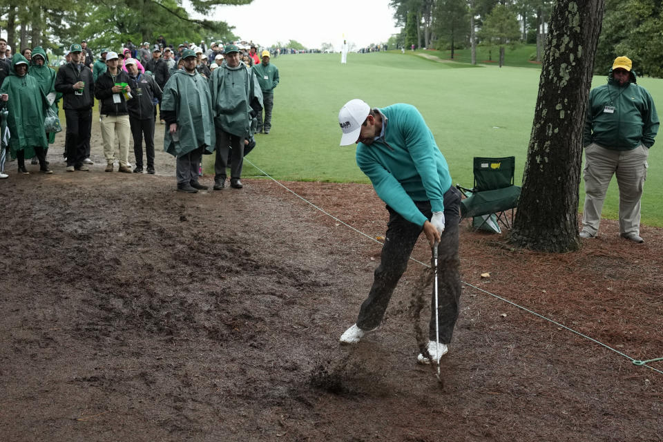 Charl Schwartzel, of South Africa, hits from the wet pine straw on the 10th hole during the weather delayed third round of the Masters golf tournament at Augusta National Golf Club on Saturday, April 8, 2023, in Augusta, Ga. (AP Photo/Charlie Riedel)