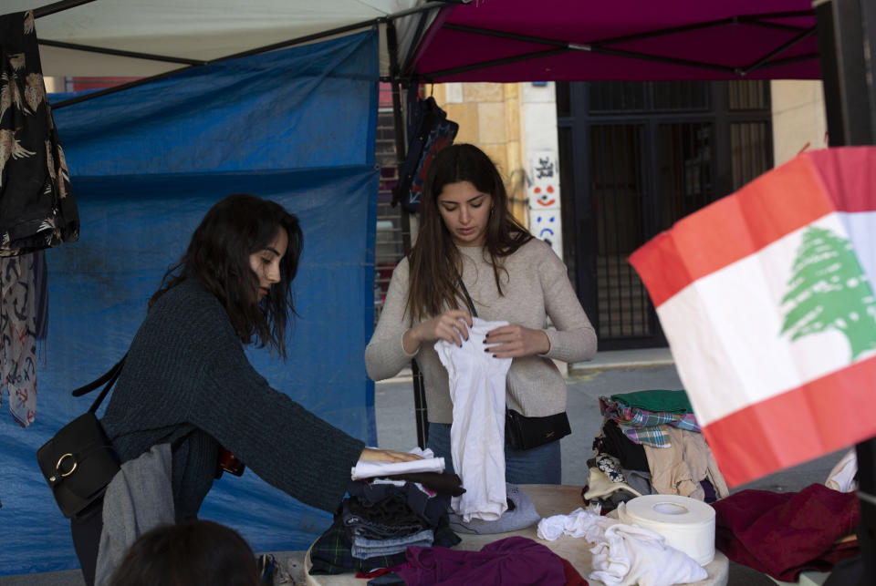 In this Sunday, Dec. 22, 2019 photo, volunteers sort donated clothing for the needy in a tent near Martyrs' Square in Beirut, Lebanon. Lebanon is entering its third month of protests, the economic pinch is hurting everyone, and the government is paralyzed. So people are resorting to what they've done in previous crises: They rely on each other, not the state. (AP Photo/Maya Alleruzzo)