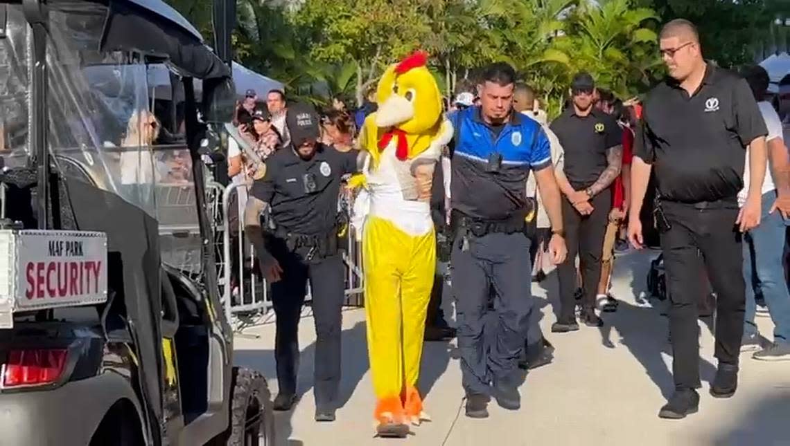 Miami police lead a protester dressed in a chicken suit away from Saturday’s unveiling of the Dogs & Cats Walkway in a downtown Miami park.