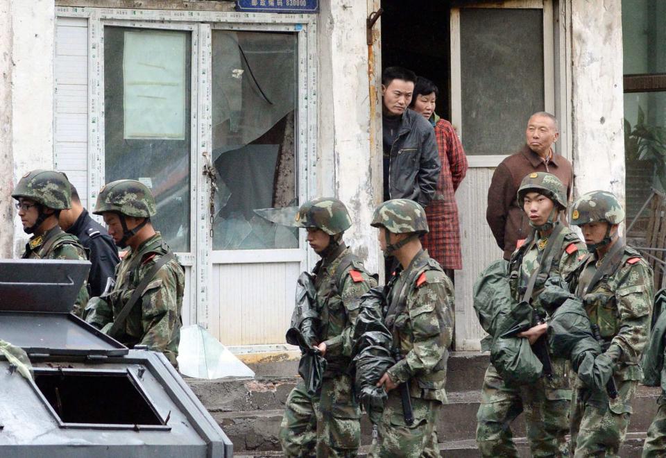 Paramilitary policemen patrol past a building, where a window was damaged by an explosion in Urumqi on Thursday, in the Xinjiang Uighur Autonomous Region, in this photo taken by Kyodo on May 22, 2014. Five suicide bombers carried out the attack which killed 31 people in the capital of China's troubled Xinjiang region, state media reported a day after the deadliest terrorist attack to date in the region. Picture taken May 22, 2014. Mandatory credit REUTERS/Kyodo (CHINA - Tags: CRIME LAW CIVIL UNREST) ATTENTION EDITORS - THIS IMAGE HAS BEEN SUPPLIED BY A THIRD PARTY. FOR EDITORIAL USE ONLY. NOT FOR SALE FOR MARKETING OR ADVERTISING CAMPAIGNS. MANDATORY CREDIT. JAPAN OUT. NO COMMERCIAL OR EDITORIAL SALES IN JAPAN. THIS PICTURE IS DISTRIBUTED EXACTLY AS RECEIVED BY REUTERS, AS A SERVICE TO CLIENTS. YES