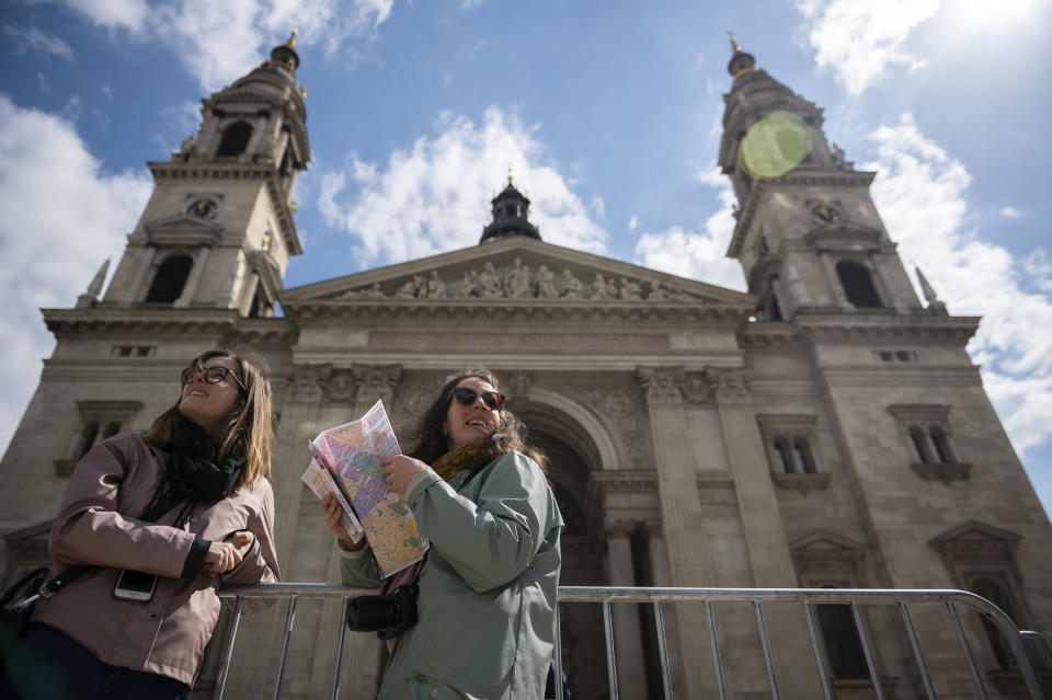 Tourists stand next to St. Stephen's Basilica in Budapest Thursday, April 27, 2023 where Pope Francis will meet with bishops, priests and pastoral workers during his visit to Hungary. Members of the Catholic community expect the pope's visit to be a celebration of Christian unity, and that a divergence of perspectives will not play a central role in Francis' visit to Hungary. (AP Photo/Denes Erdos)