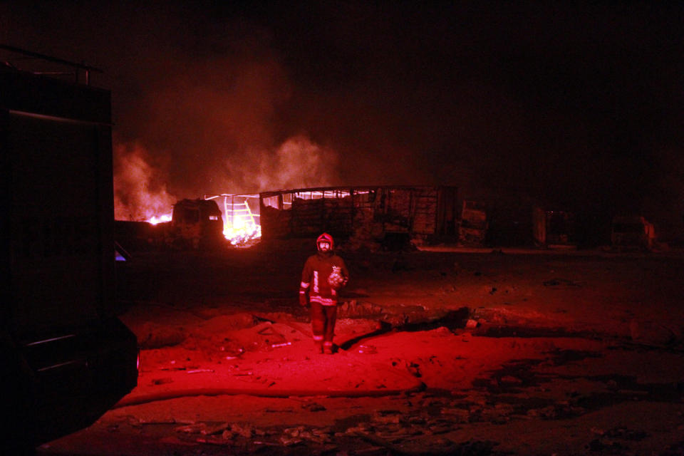 One of the Iranian firefighters works on a burning tanker carrying fuel at the Islam Qala border with Iran, in Herat Province, west of Kabul, Afghanistan, Saturday, Feb. 13, 2021. A fuel tanker exploded Saturday at the Islam Qala crossing in Afghanistan's western Herat province on the Iranian border, injuring at least seven people and causing a massive fire that consumed more than 500 trucks carrying natural gas and fuel, according to Afghan officials and Iranian state media. (AP Photo/Hamed Sarfarazi)