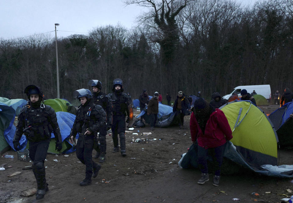 In this photo taken on Wednesday Jan. 16, 2019 police officers dismantle a migrants makeshift camp in Calais, northern France. Border control officers patrolling the land, sea and air of northern France are combing beaches, dunes and the frigid, murky coastal waters in a bid to end a high-risk but growing tactic by a group of mostly Iranian migrants desperate to get to Britain: sneaking across the English Channel in rubber boats. (AP Photo/Michel Spingler)