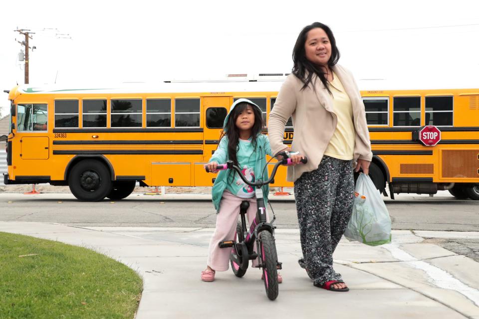 Marianne Alapaid and her daughter, 7 year old Jazne Alapaid walk home after picking up school breakfast and lunch provided by Palm Springs Unified School District in Palm Springs, Calif. on Wednesday, March 18, 2020. Schools closed due to the coronavirus outbreak.