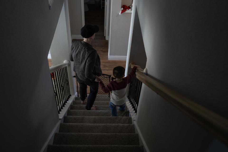 Erica holds August's hand as they make their way down the stairs of their Mckinney home on Dec. 9, 2023.