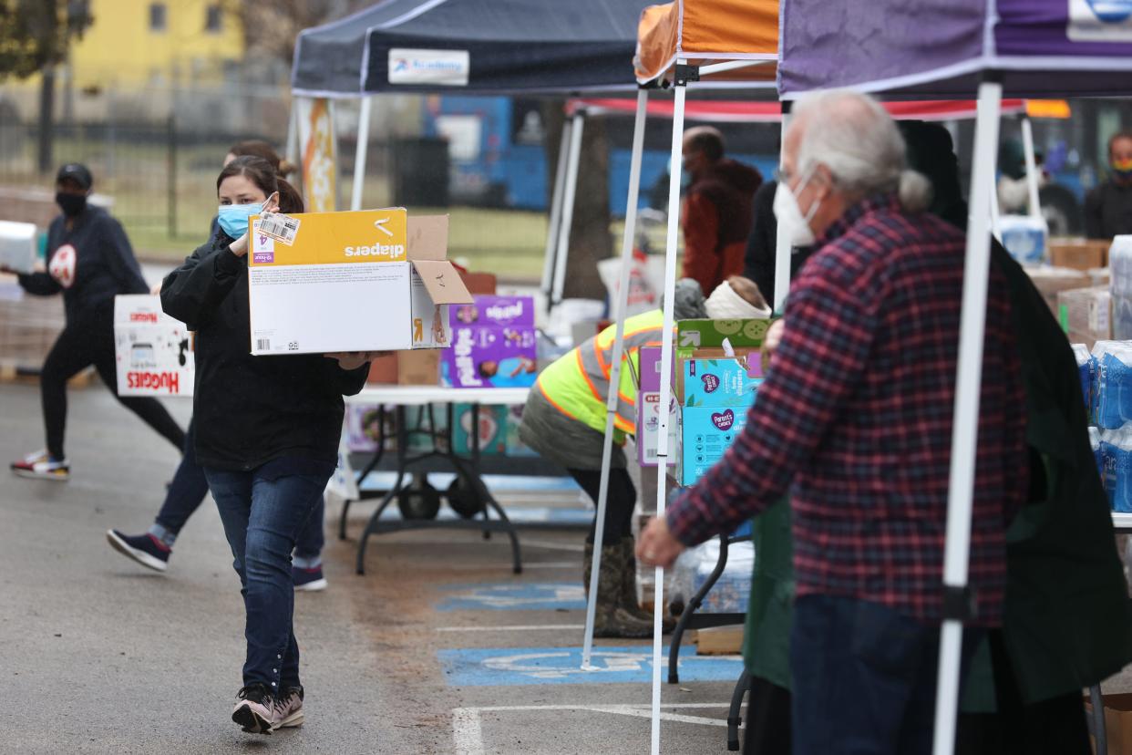 Workers help to dispense food, water and hygiene products to people in need at the Millennium Entertainment Center food distribution site in East Austin on Thursday, Feb. 25, 2021. 