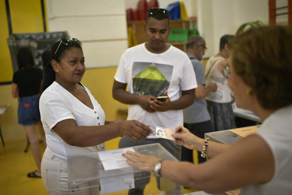 A woman shows her ID as she votes at a polling station in Pamplona, Spain, Sunday July 23, 2023. Spain is holding general elections, that could make the country the latest European Union member to swing to the political right, at the height of summer, when millions of citizens are likely to be vacationing away from their regular polling places.(AP Photo/Alvaro Barrientos)