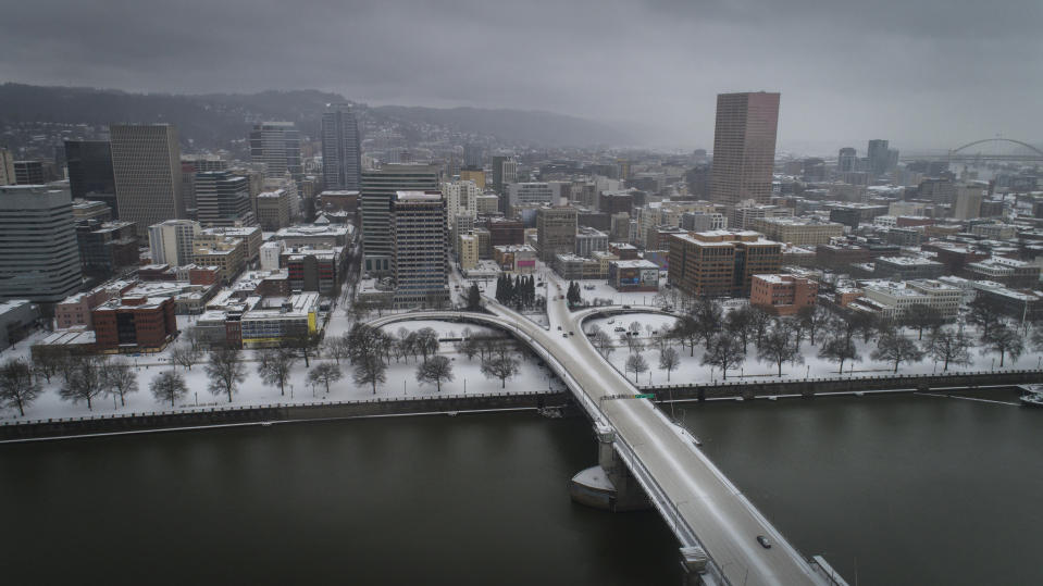 An aerial view of the Morrison Bridge and downtown Portland, Ore., is seen during a snowstorm, on Friday, Feb. 12, 2021. A winter storm has blanketed the Pacific Northwest with ice and snow, leaving hundreds of thousands of people without power and disrupting travel across the region. (Brooke Herbert/The Oregonian via AP)