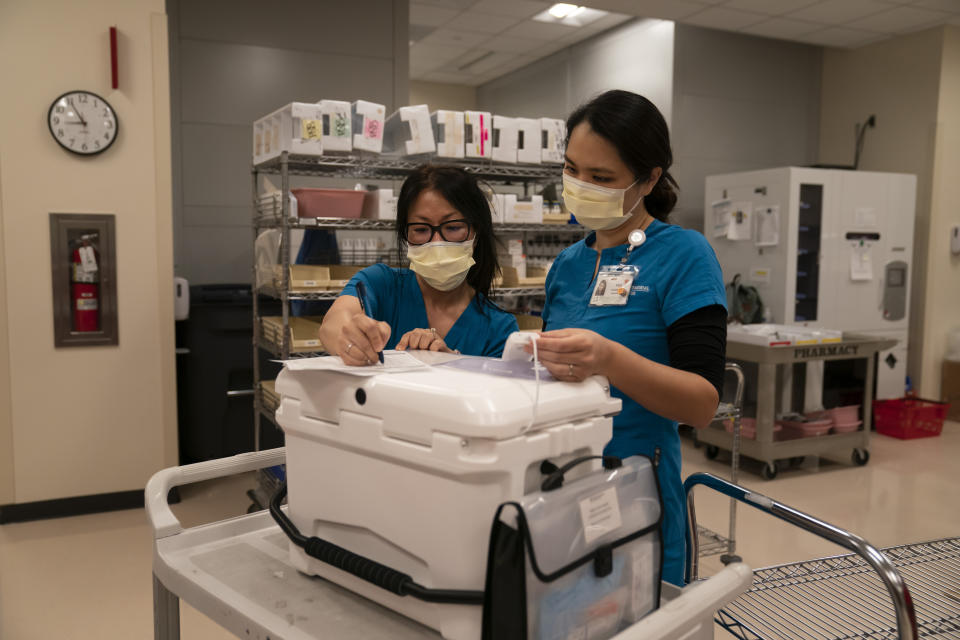 Pharmacists Stella Kim, left, and Mei Tsai check the temperature of a cooler containing the Pfizer COVID-19 vaccine before heading out to inoculate two sisters, who have muscular dystrophy, at their home, Wednesday, May 12, 2021, in Torrance, Calif. Torrance Memorial Medical Center started inoculating people at home in March, identifying people through a city hotline, county health department, senior centers and doctor's offices, said Tsai, who coordinates the program. (AP Photo/Jae C. Hong)