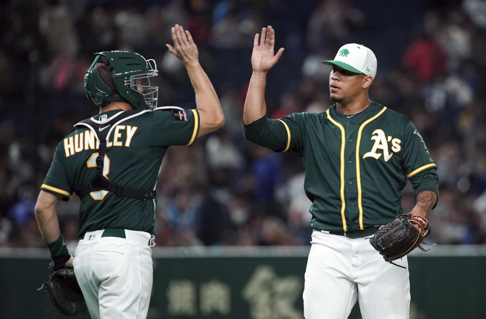 Oakland Athletics closer Frankie Montas, right, and catcher Nick Hundley celebrate their 5-1 victory over the Nippon Ham Fighters in their pre-season exhibition baseball game at Tokyo Dome in Tokyo Sunday, March 17, 2019. (AP Photo/Eugene Hoshiko)