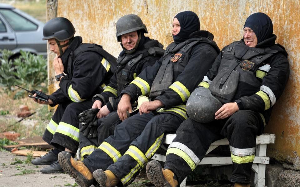 Firefighters rest after extinguishing a fire at the site of a Russian missile strike