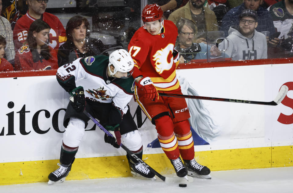 Arizona Coyotes defenseman Vladislav Kolyachonok (52) steals the puck from Calgary Flames forward Yegor Sharangovich (17) during the first period of an NHL hockey game in Calgary, Alberta, Sunday, April 14, 2024. (Jeff McIntosh/The Canadian Press via AP)