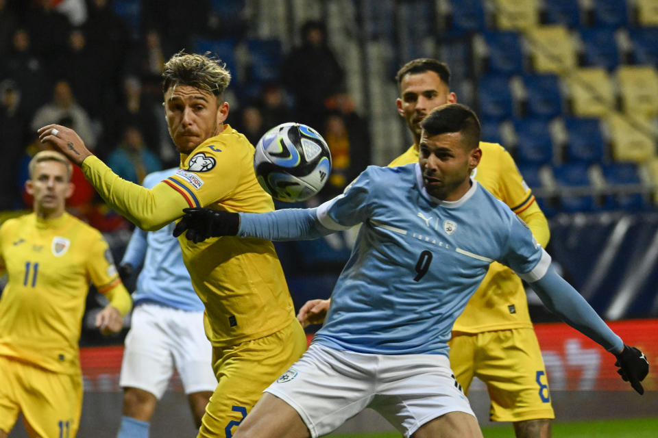 Romania's Andrei Ratiu, left, duels for the ball with Israel's Tai Baribo during the Euro 2024 group I qualifying soccer match between Israel and Romania at the Pancho Arena in Felcsut, Hungary, Saturday, Nov. 18, 2023. (AP Photo/Denes Erdos)