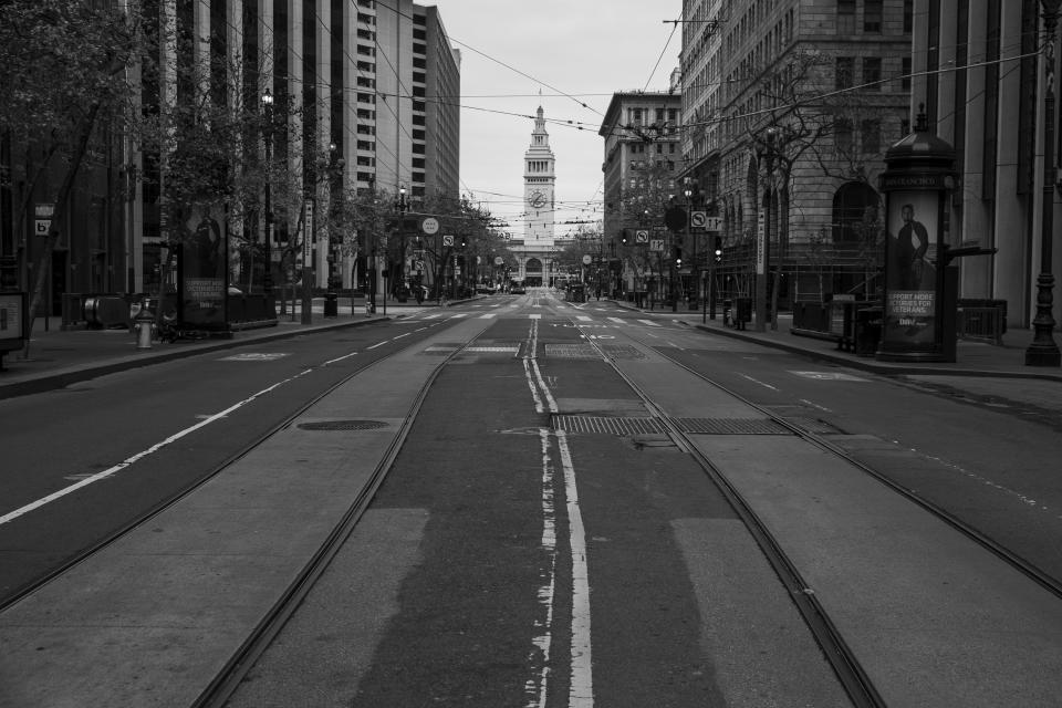 Market Street is mostly empty with the Ferry Building in the background in San Francisco on April 17, 2020. Normally, the months leading into summer bring bustling crowds to the city's famous landmarks, but this year, because of the coronavirus threat they sit empty and quiet. Some parts are like eerie ghost towns or stark scenes from a science fiction movie. (AP Photo/Eric Risberg)