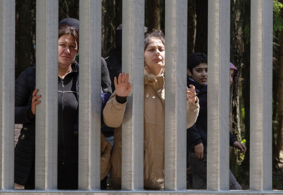 Members of a group of some 30 migrants seeking asylum are seen in Bialowieza, Poland, on Sunday, 28 May 2023 across a wall that Poland has built on its border with Belarus to stop massive migrant pressure. The group has remained stuck at the spot for three days, according to human rights activists. (AP Photo/Agnieszka Sadowska)