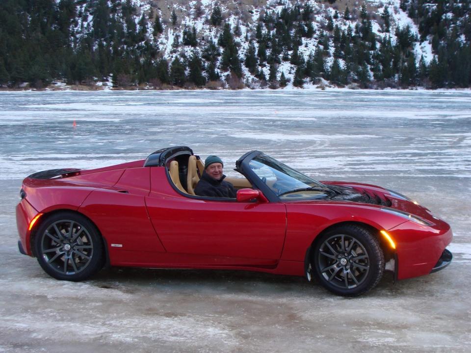 Nigel Zeid driving red electric convertible on an icy track in a snow-covered forest.