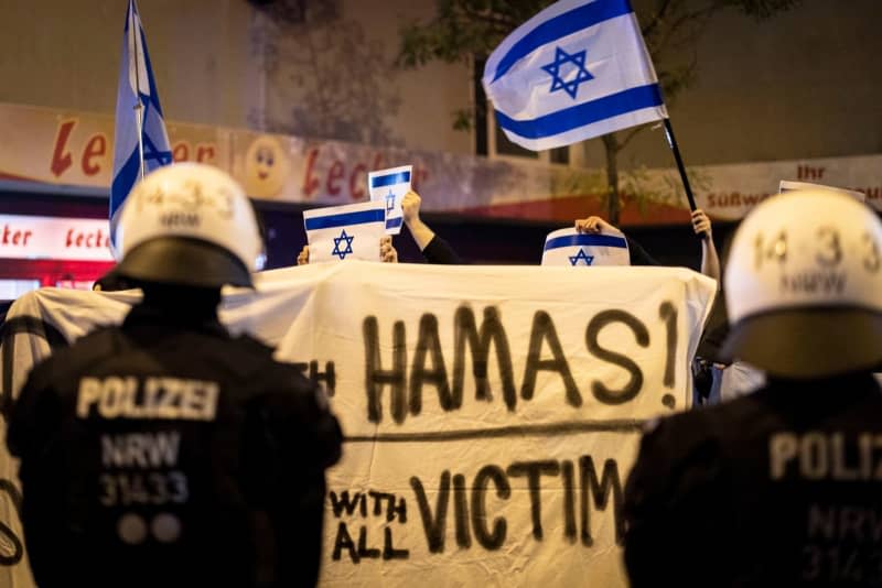 Counter-demonstrators display Israeli flags and a banner against Hamas at the end of a pro-Palestinian rally at Brueckenplatz. Christoph Reichwein/dpa