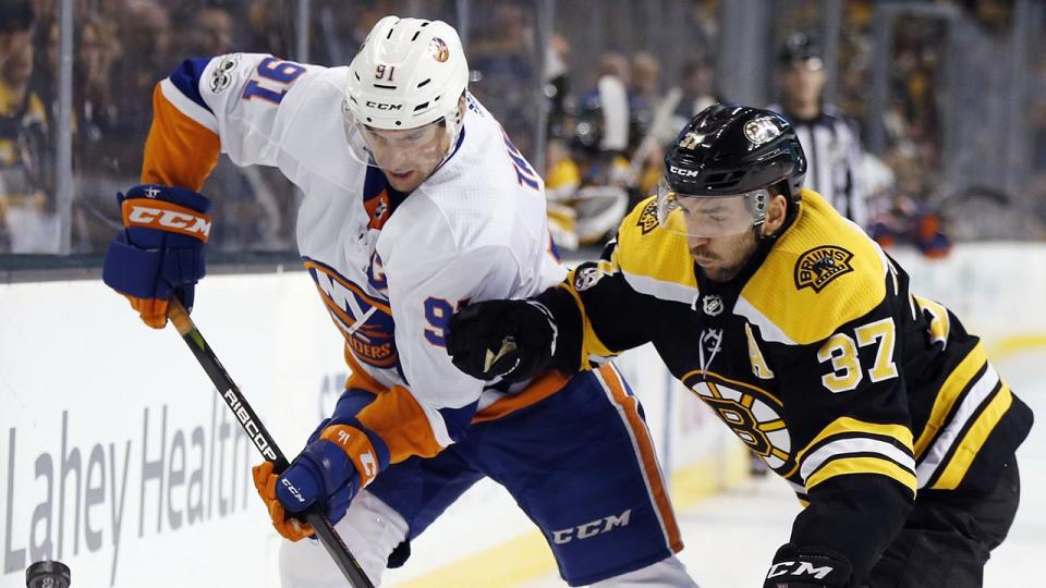 New York Islanders' John Tavares (91) and Boston Bruins' Patrice Bergeron (37) battle for the puck during the third period of an NHL hockey game in Boston, Saturday, Dec. 9, 2017. (AP Photo/Michael Dwyer)