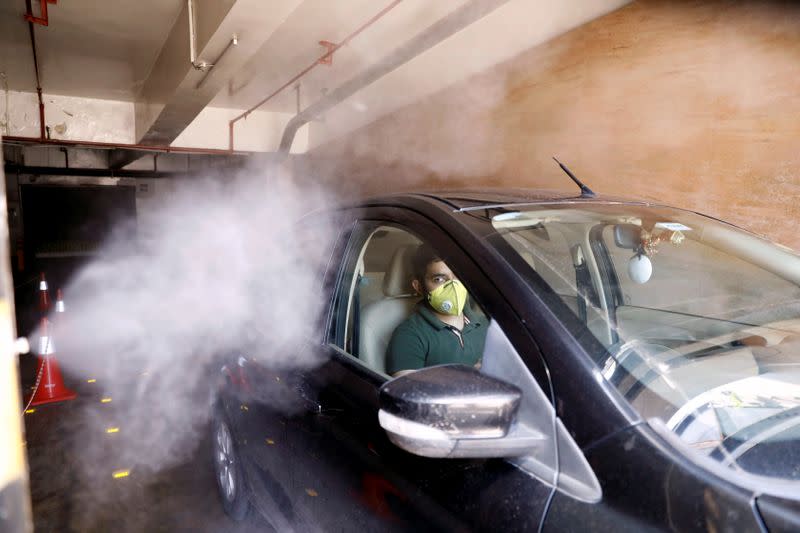 A car is sanitised at the entrance of a mall as part of a demonstrated sanitisation procedure by mall authorities ahead of its reopening during an extended nationwide lockdown to slow down the spread of the coronavirus disease (COVID-19), in New Delhi