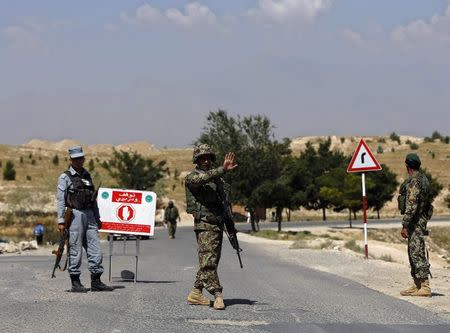 An Afghan National Army (ANA) soldier gestures to stop vehicles at a check point near the British-run military training academy Camp Qargha, in Kabul August 6, 2014. REUTERS/Omar Sobhani