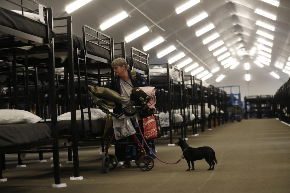 File - In this Dec. 1, 2017, file photo, Verna Vasbinder prepares her new bunk in the city's new Temporary Bridge Shelter for the homeless as her dog, Lucy Lui, looks on in San Diego. A new federal report says the number of people living on the streets in Los Angeles and San Diego, two epicenters of a West Coast homelessness crisis, fell this year, suggesting possible success in those cities' efforts to combat the problem. Homelessness overall was up slightly across the country, although the report did not provide a complete picture of the problem. (AP Photo/Gregory Bull, File)