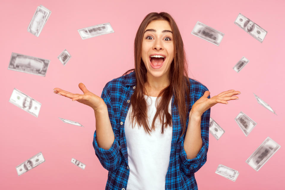 Oh my god, wow. Portrait of amazed young woman looking at camera with big eyes, absolutely shocked of money rain falling from up. indoor isolated on pink background