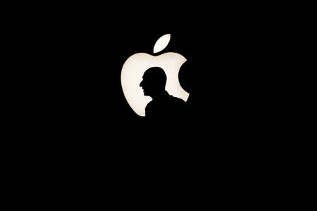 A man walks past a backlit Apple logo during an Apple media event in San Francisco, California, in this September 9, 2015 file photo. REUTERS/Beck Diefenbach/Files