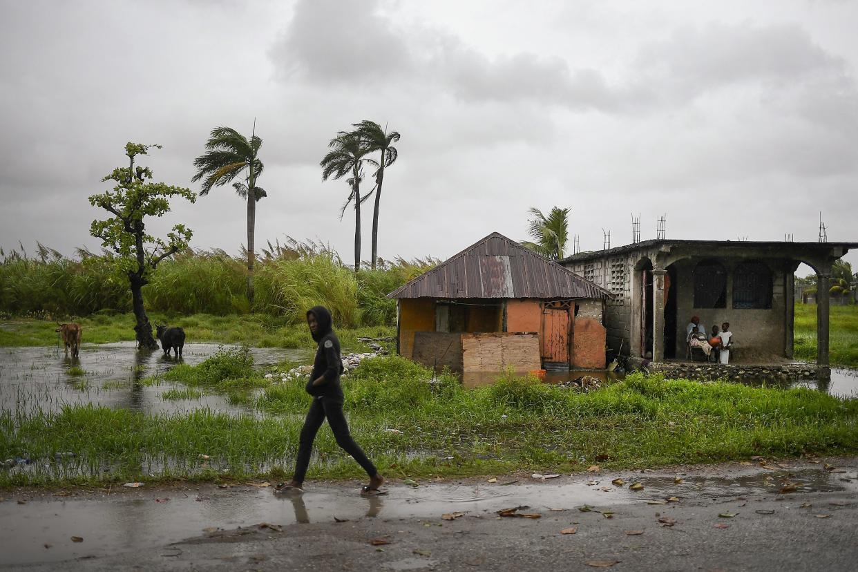 A man walks along a road in a slightly flooded area the morning after Tropical Storm Grace swept over the area in Trou Mahot, Haiti, Tuesday, Aug. 17, 2021, three days after a 7.2-magnitude earthquake.