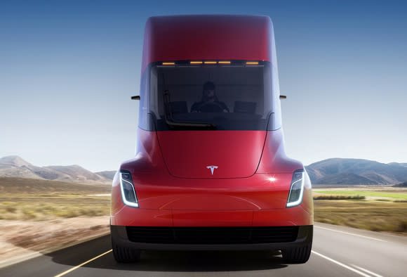 A head-on view of a red Tesla Semi, an electric tractor-trailer truck, on a desert highway.