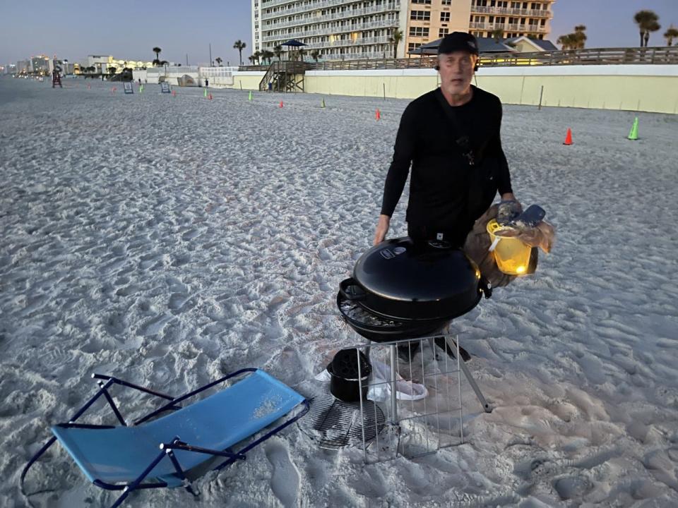 Daytona Beach resident Warren Oldroyd, a volunteer picking up trash left by July 4 party-goers, finds a beach chair and grill left on the sand near Sun Splash Park in Daytona Beach.
