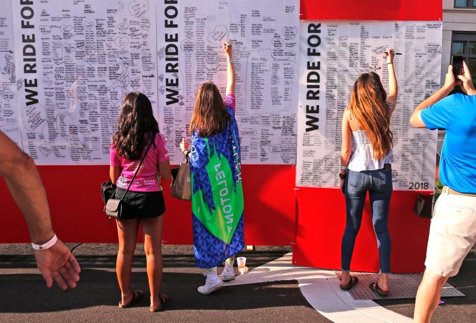 Cate Warnement, 18, of Columbus writes a name on the board of rider tributes during the Pelotonia opening ceremony at McFerson Commons in 2018.