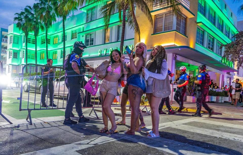 Un grupo de vacacionistas de primavera de Georgia tomándose "selfies" mientras caminan junto a un puesto de policía en Ocean Drives durante las vacaciones de primavera en Miami Beach el sábado 16 de marzo de 2024.