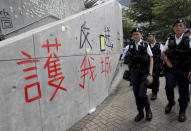 Hong Kong police officers pass by words formed with tape which read "Protect our city, against extradition to China" near the Legislative Council in Hong Kong on Friday, June 14, 2019. Calm appeared to have returned to Hong Kong after days of protests by students and human rights activists opposed to a bill that would allow suspects to be tried in mainland Chinese courts. (AP Photo/Vincent Yu)