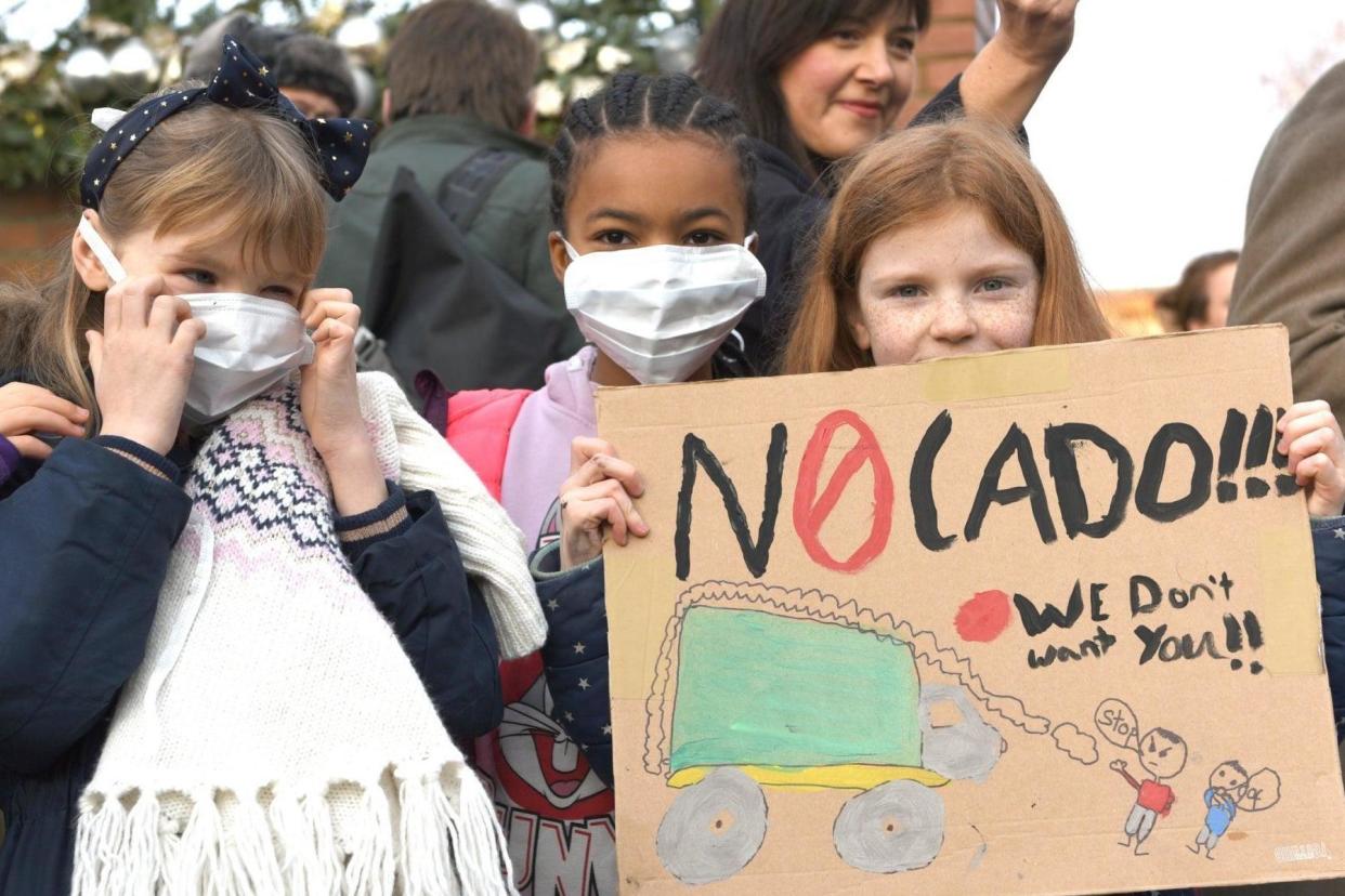 Concerned: children wear face masks and wave placards in protest