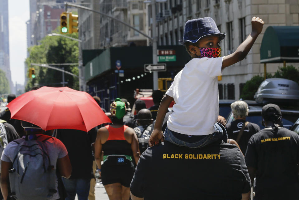 A man carries a child as they march near Central Park, during a Juneteenth celebration Friday, June 19, 2020, in New York. Juneteenth commemorates when the last enslaved African Americans learned they were free 155 years ago. Now, with support growing for the racial justice movement, 2020 may be remembered as the year the holiday reached a new level of recognition.(AP Photo/Frank Franklin II)